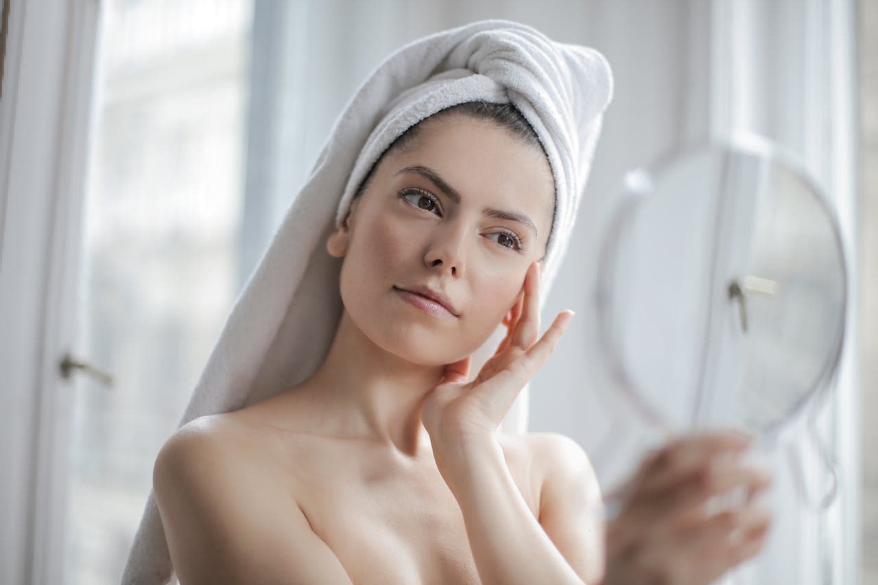 Glowing skin reflected in a hand mirror at Illari Aesthetics